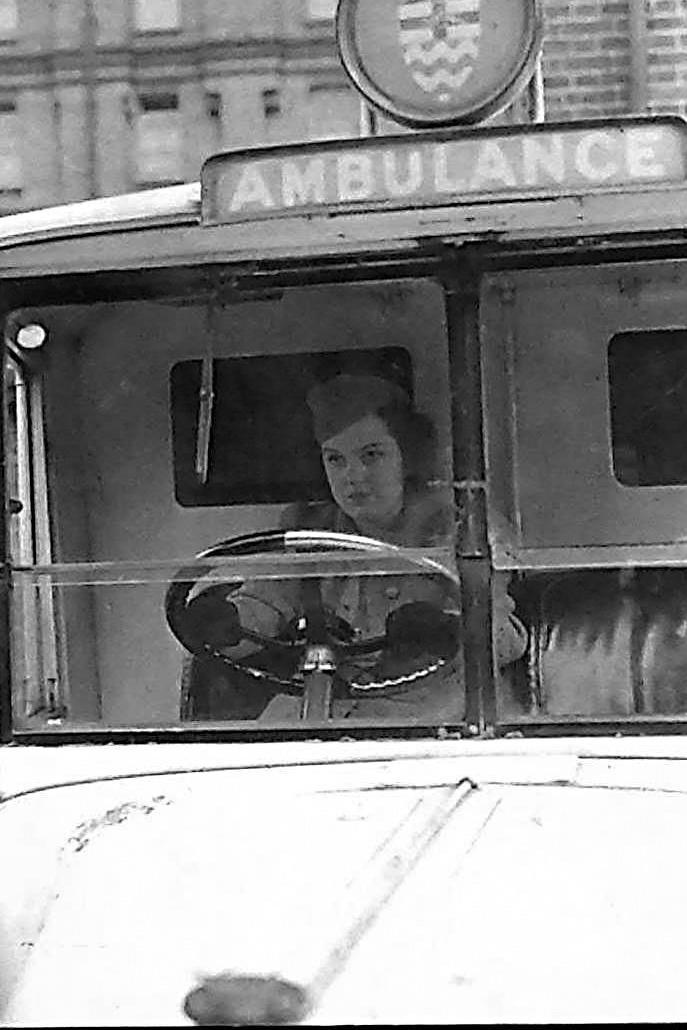 A women with dark hair behind the wheel of an ambulance 