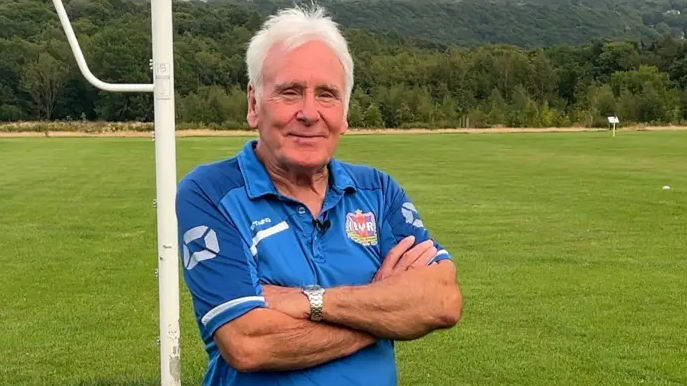 Martin Windle from Ecclesall Rangers looks at the camera with his arms folded. He's got white hair and has a blue football shirt on. He's standing between two goalposts - one of which is in the foreground of the photo.