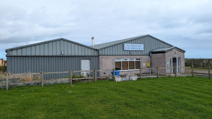 Togalach glas air feur uaine, agus soidhne air le Tiree Rural Centre sgrìobhte air.