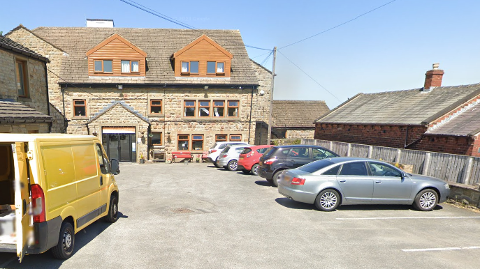 The outside of a three-storey property, including a car park with parked cars.