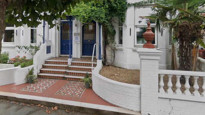 Steps between low, white brick walls lead to double doors at the entrance to Sandown House.