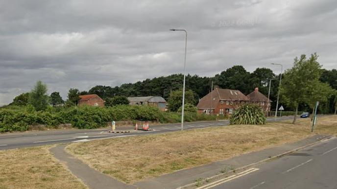 Google Street View of Scotter Road with street lights and trees in the foreground and houses in the background