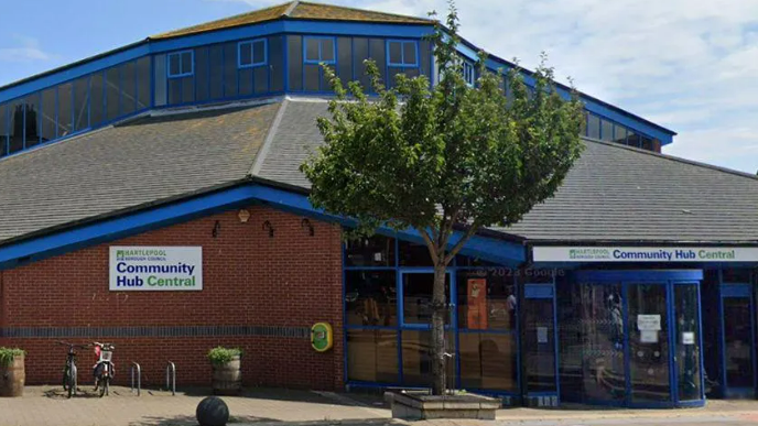 A library building with a sign saying Community Hub Central outside 