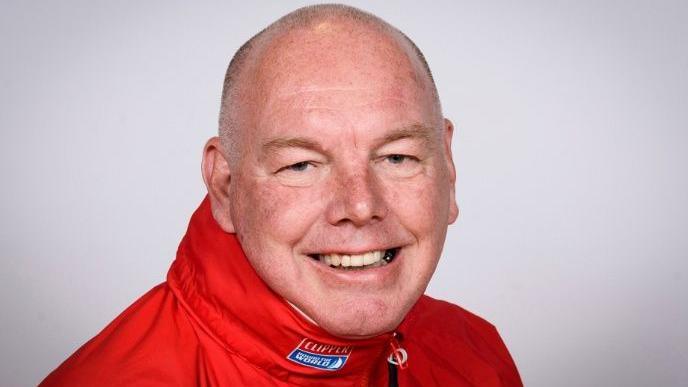 Mark Perkins smiling and wearing a red event jacket