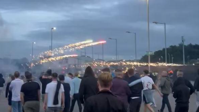 Shows large groups of people watching flares overhead 
