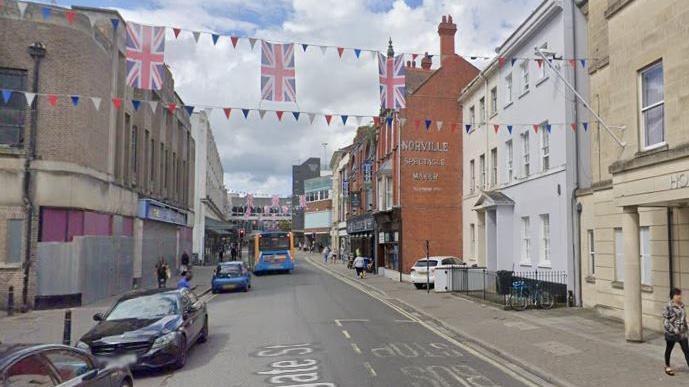 General view of Gloucester city centre with buses and vehicles along the street. Some businesses are boarded up.