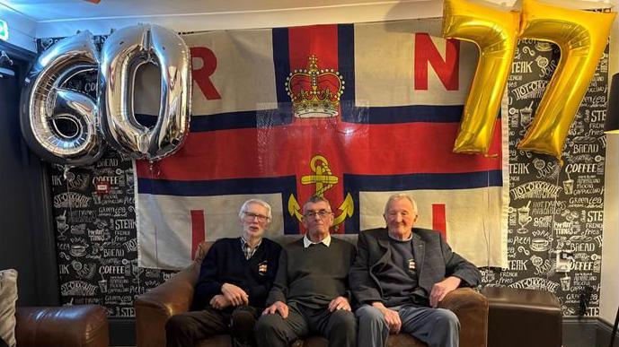 Richard Spindler, sat on a brown leather sofa with RNLI crew mates Julian Morris and Anthony Blizzard