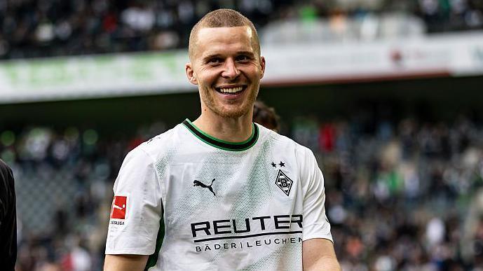 Nico Elvedi smiling to camera while wearing Monchengladbach's white and green shirt