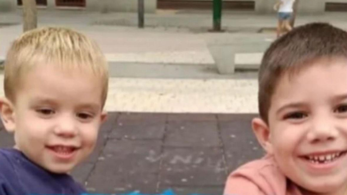 Rubén and Izan Matías, two young boys, are stood outside and are smiling at the camera. The photo only shows their heads and shoulders
