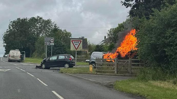 Scene of crash with one of the two vehicles on fire