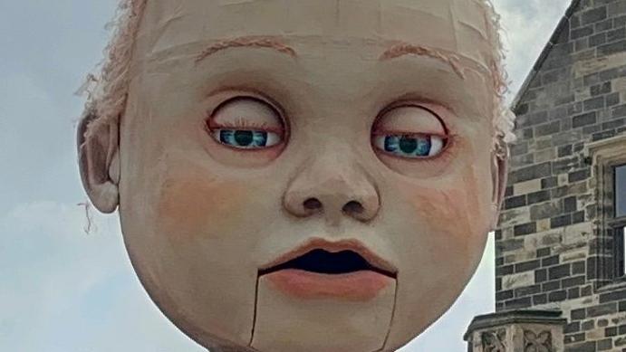 A close-up of the giant puppet's face, with its eyes half closed.