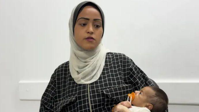 An image of Najah, a 19-year-old woman, holding a baby in her arms.