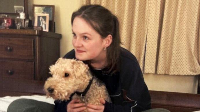 Lucy Atkins cuddling the family dog, Simba on a bed