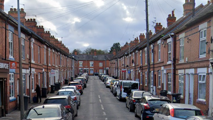 A terraced street with cars parked either side of the road 