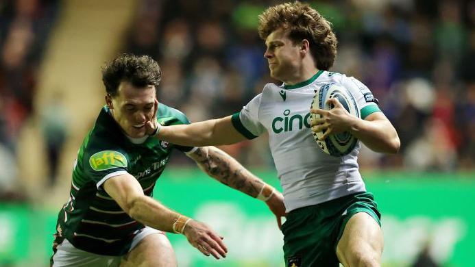 Jake Garside holds off an opponent as he charges forward with the ball