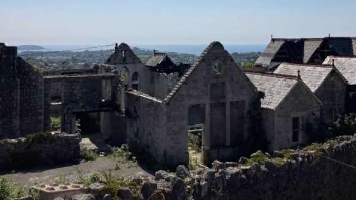 The former Carclaze school pictured after a fire left the building gutted in 2020. The building left is made of brick and is ruined. The sky is blue.