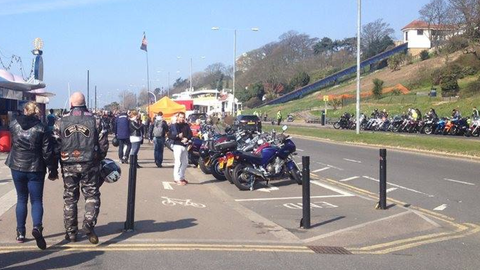 People walking along Southend seafront, which is lined with motorcycles.