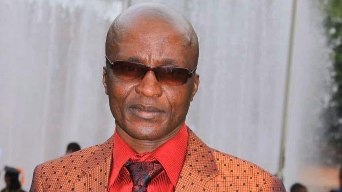 Andile Mvuyelwa Somgxada in sunglasses wearing a red shirt maroon patterned tie and an orange and brown check tailored jacket