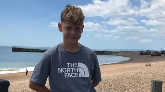 Harry Dennis, who died in the crash, is pictured on a stone beach. He has sandy blonde hair and is wearing a T-shirt from The North Face.