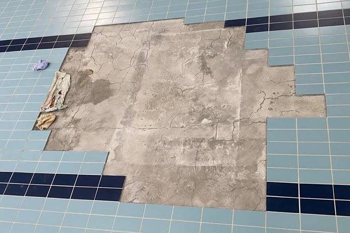 A grey area of floor revealed after damaged blue swimming pool tiles were removed.