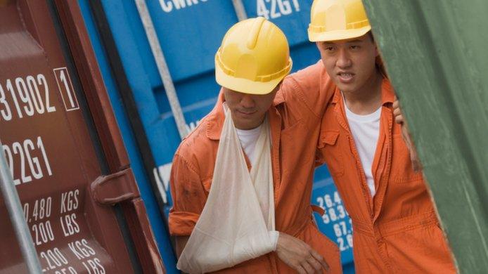 An injured dock worker being helped by a co-worker