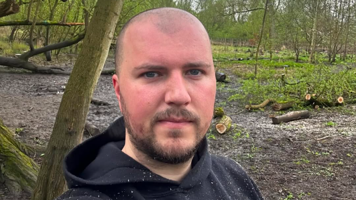 Jack Langston, in a forest, looking stern
