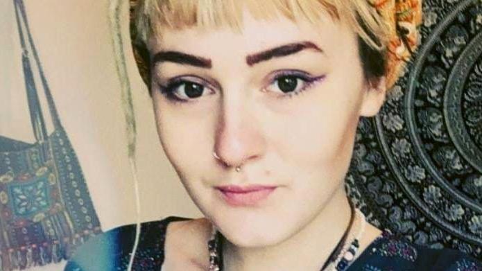 A close-up of Jodi Jayne Walsham, who has blonde hair tied up and dark eyebrows and a pierced nose. She is wearing a necklace and a colourful shirt.