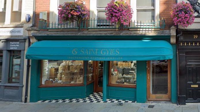 Exterior of Saint Gyles Jewellers with turquoise frontage and rings etc in the window