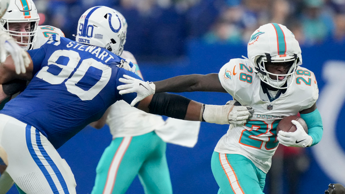 Miami Dolphins running back De'Von Achane runs with the ball as Indianapolis Colts defensive tackle Grover Stewart reaches out to tackle him