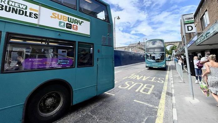 View of the back of a bus and the front of another on a street in Durham City Centre