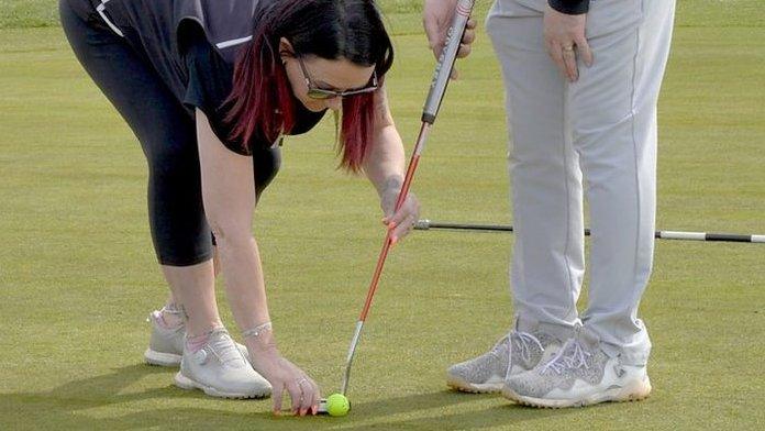 Andy Gilford's wife Mel helps line up a putt