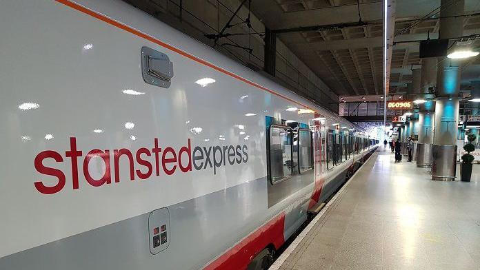 A white and grey train at a platform with the words "Stansted Express" on the side.