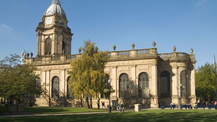 St Philip’s Cathedral. It is a grand building surrounded by green space. Some people can be seen outside. 