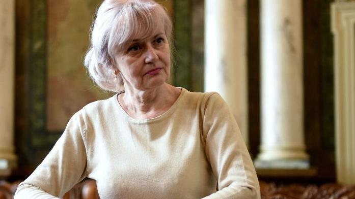 Iryna Farion the ex-Ukrainian MP - poses for an official press photograph. She's wearing a cream coloured long sleeve top and is looking towards the right of the frame.