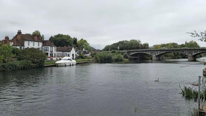 A picture of the River Thames supplied by Surrey Police. A bridge can be seen in the image alongside two buildings and a boat.