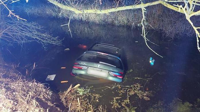 A BMW car nearly fully submerged in a pong