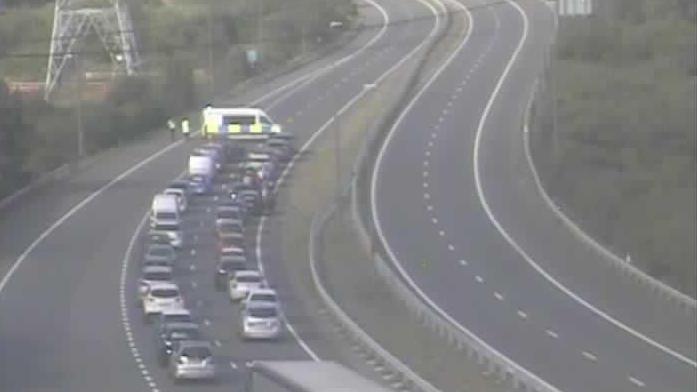 A traffic camera picture of the M49, showing traffic being held by police. A row of cars is shown queued up behind a police van parked sideways on the road. 