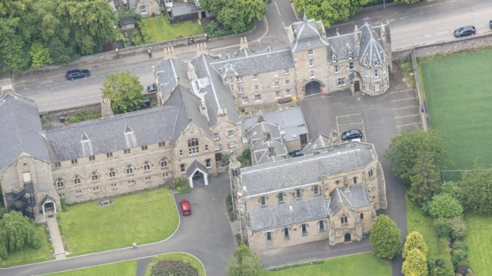 A set of historic buildings surrounded by grass and trees from above