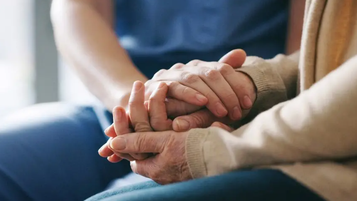 An elderly woman's hands and a carer's hands placed on top of each other 