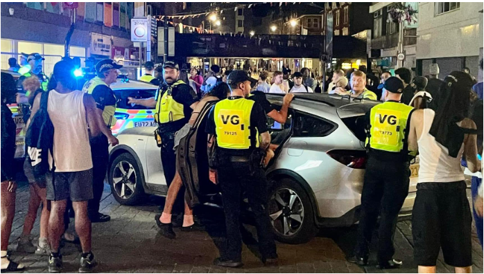 Police officers next to a car in Southend with a crowd of people behind it