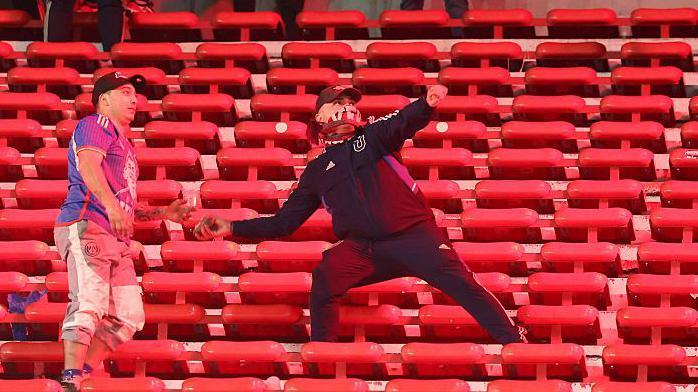 A Universidad de Chile fan prepares to throw an object during their game away to Independiente in August 2025