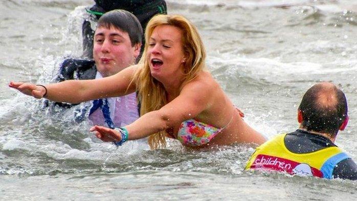 A woman in a bikini and man in a suit swim