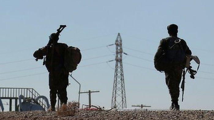 Syria Democratic Forces (SDF) fighters carry their weapons as they walk near the town of Tel al-Saman in the northern rural area of Raqqa, Syria