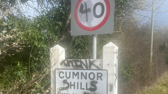 Defaced speed limit sign and a graffitied slogan