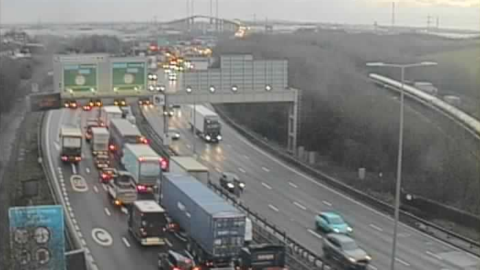 Traffic queuing on the A282 in rain, below a gantry with large green signs