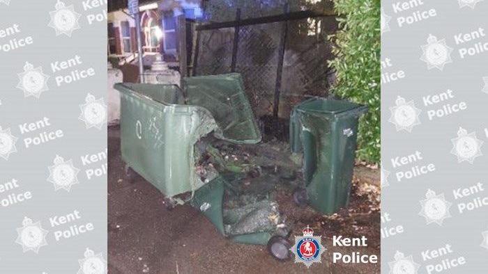 Burnt big green wheelie bins. They are disfigured, charred and half melted.