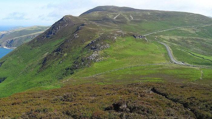 The Sloc road winds over the green hills on the Isle of Man coast.