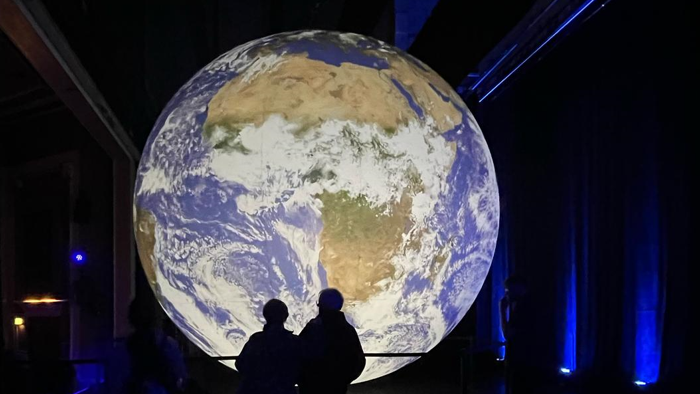 Silhouettes of people in front of a large illuminated globe
