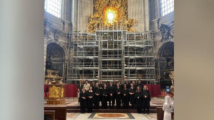 The choir standing at St Peter's Basilica after their performance. There is scaffolding behind them.