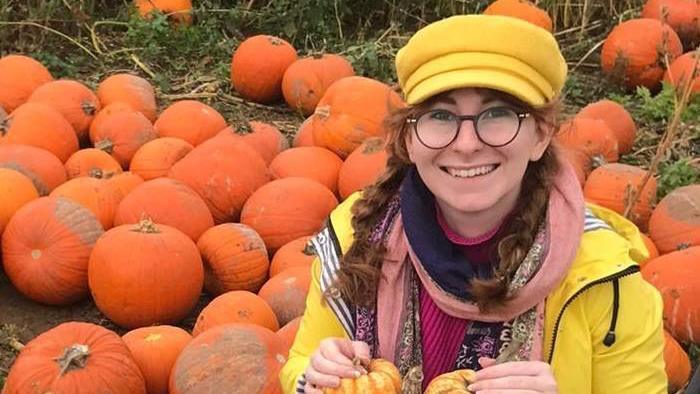 Gynaecology patient Bethany smiles from home with glasses on and a streak of bleached hair.